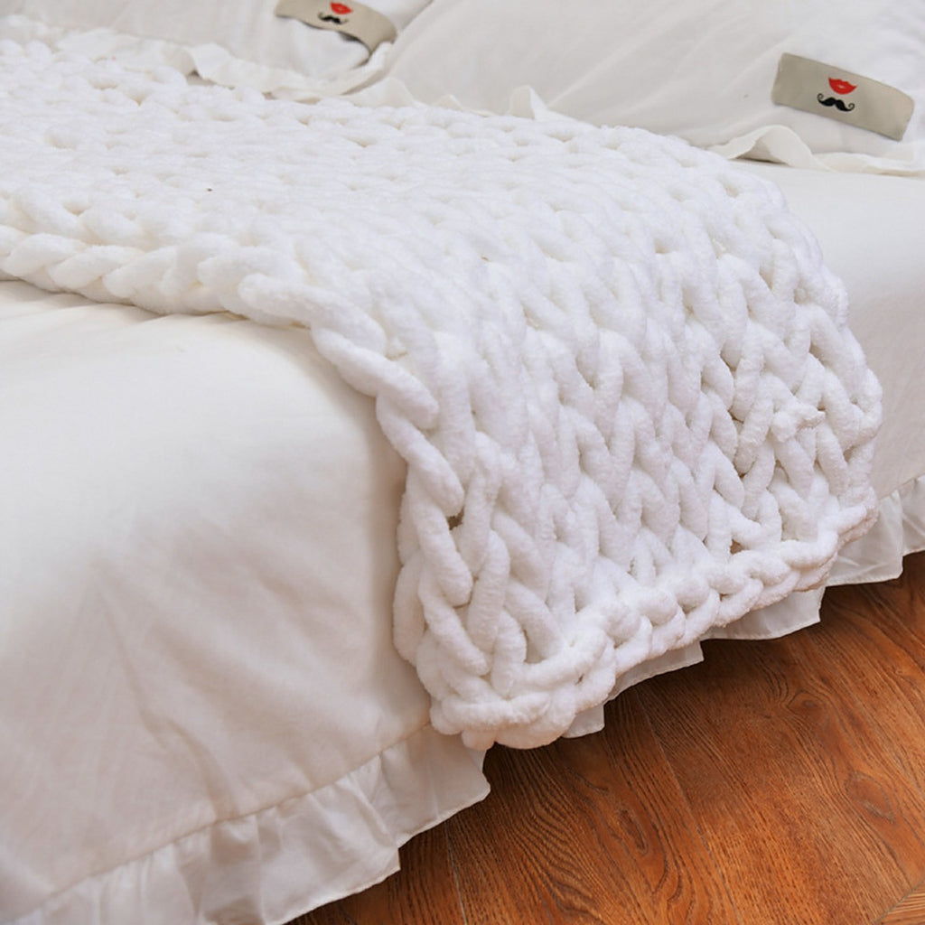 The Anchor chunky knit blanket in white, spread across a made bed