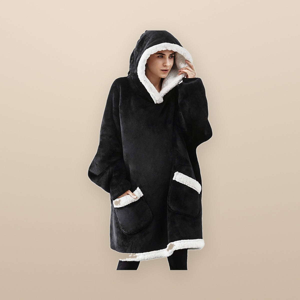 The Burrow oversized hoodie blanket in black, worn with the hood up, showing the white sherpa lining