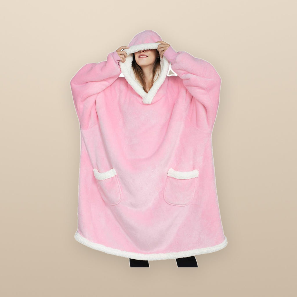 The Burrow oversized hoodie blanket in pink, worn with both hands holding the hood